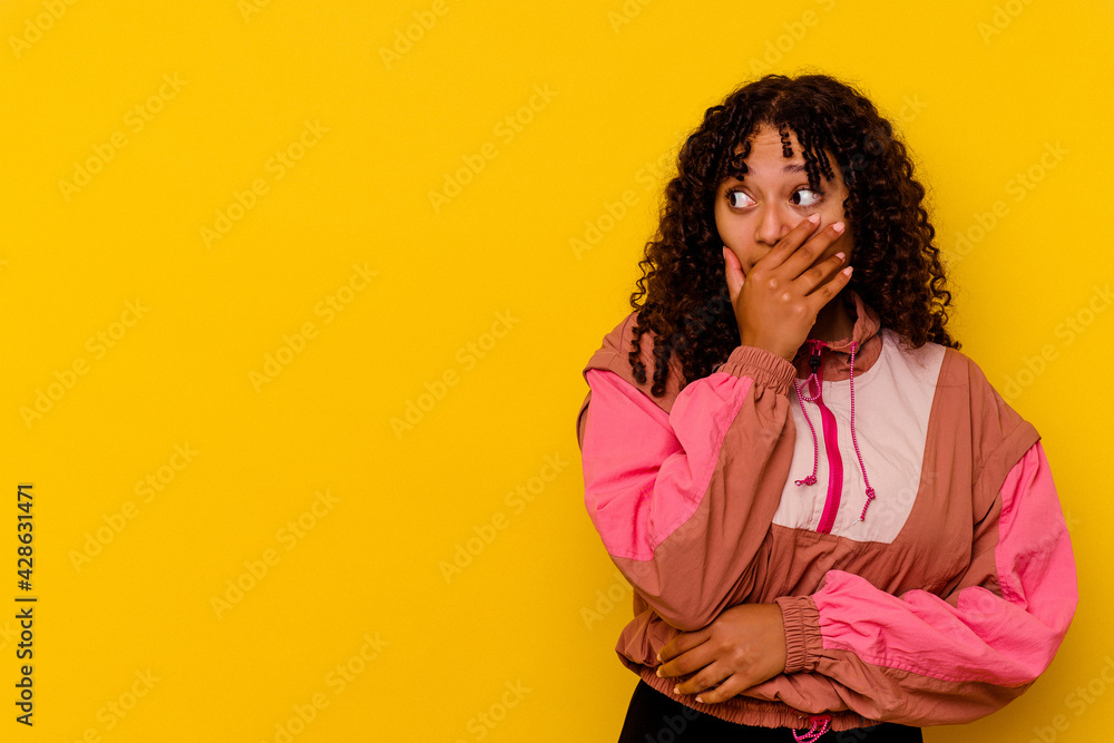 Young mixed race woman isolated on pink background thoughtful looking to a copy space covering mouth with hand. Young mixed race woman isolated on pink background thoughtful looking to a copy space covering mouth with hand.