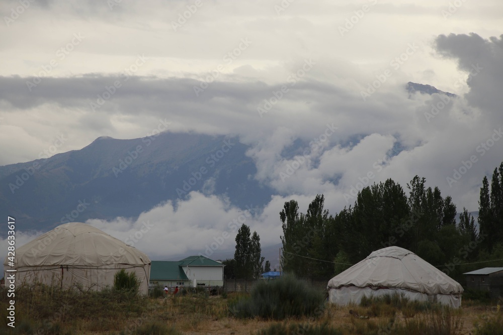 fluffy white clouds rise above the yurts in the village.
Clouds in the mountains 