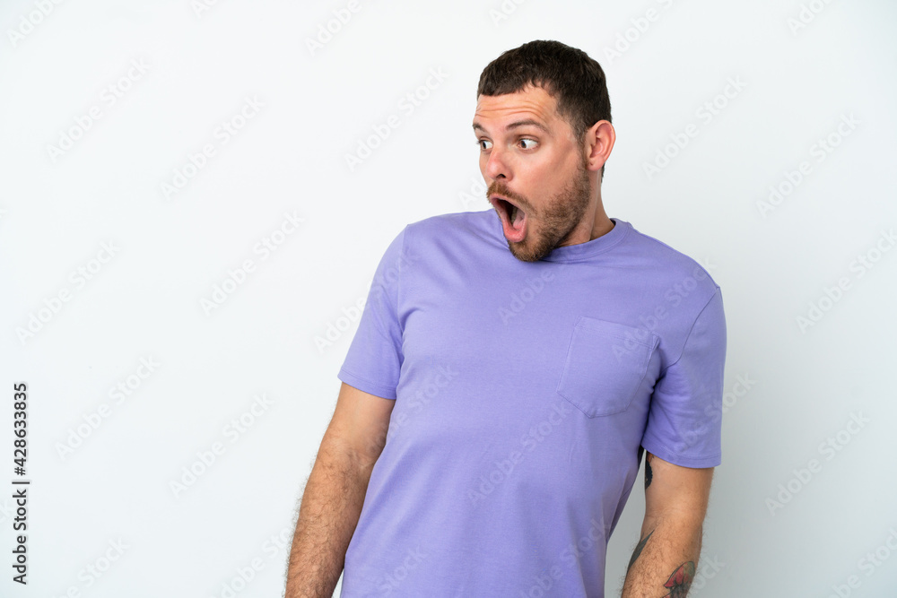 Young Brazilian man isolated on white background doing surprise gesture while looking to the side Young Brazilian man isolated on white background doing surprise gesture while looking to the side
