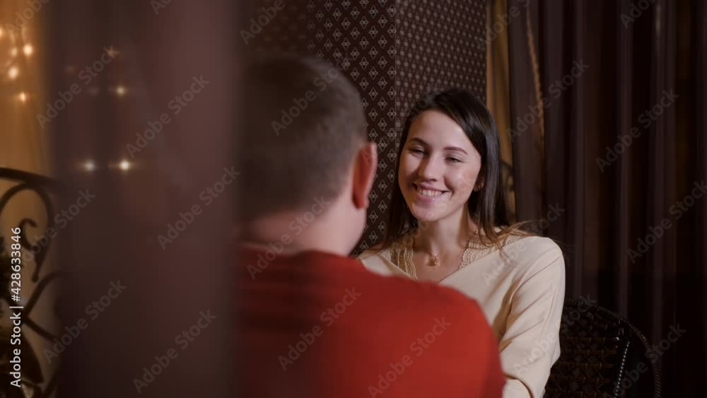 Portrait smiling woman sitting at table in cafe on romantic date with man. Happy woman laughing on evening rendezvous in romantic restaurant Portrait smiling woman sitting at table in cafe on romantic date with man. Happy woman laughing on evening rendezvous in romantic restaurant