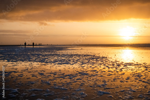 Spaziergänger bei Sonnenuntergang am Strand der Nordseeinsel Langeoog