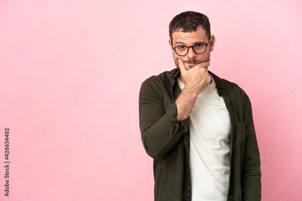Young Brazilian man isolated on pink background having doubts Young Brazilian man isolated on pink background having doubts