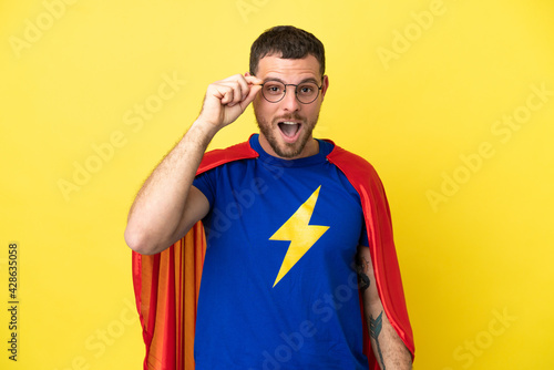 Super Hero Brazilian man isolated on yellow background with glasses and surprised