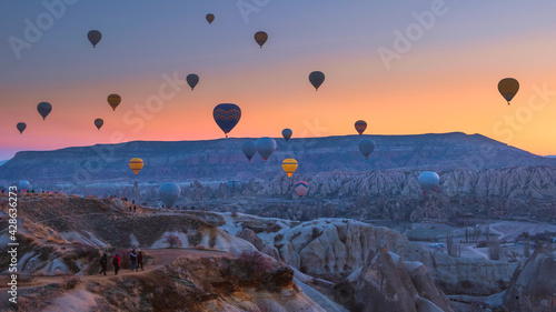 hot air balloons fly at sunrise over the mountains in Cappadocia Turkey