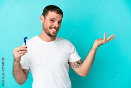 Brazilian man shaving his beard isolated on blue background extending hands to the side for inviting to come