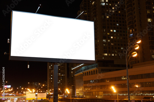 Large horizontal billboard in the night city next to skyscrapers.
