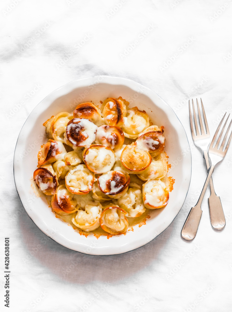Baked cheese tortellini in a baking dish on a light background, top view Baked cheese tortellini in a baking dish on a light background, top view