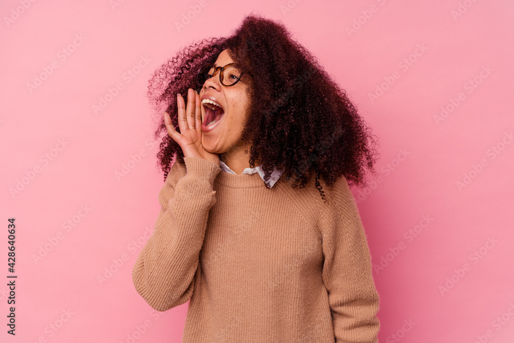 Young african american woman isolated on pink background shouting and holding palm near opened mouth. Young african american woman isolated on pink background shouting and holding palm near opened mouth.