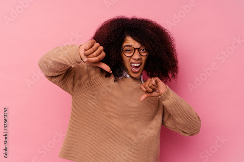 Young african american woman isolated on pink background showing thumb down and expressing dislike. © Asier
