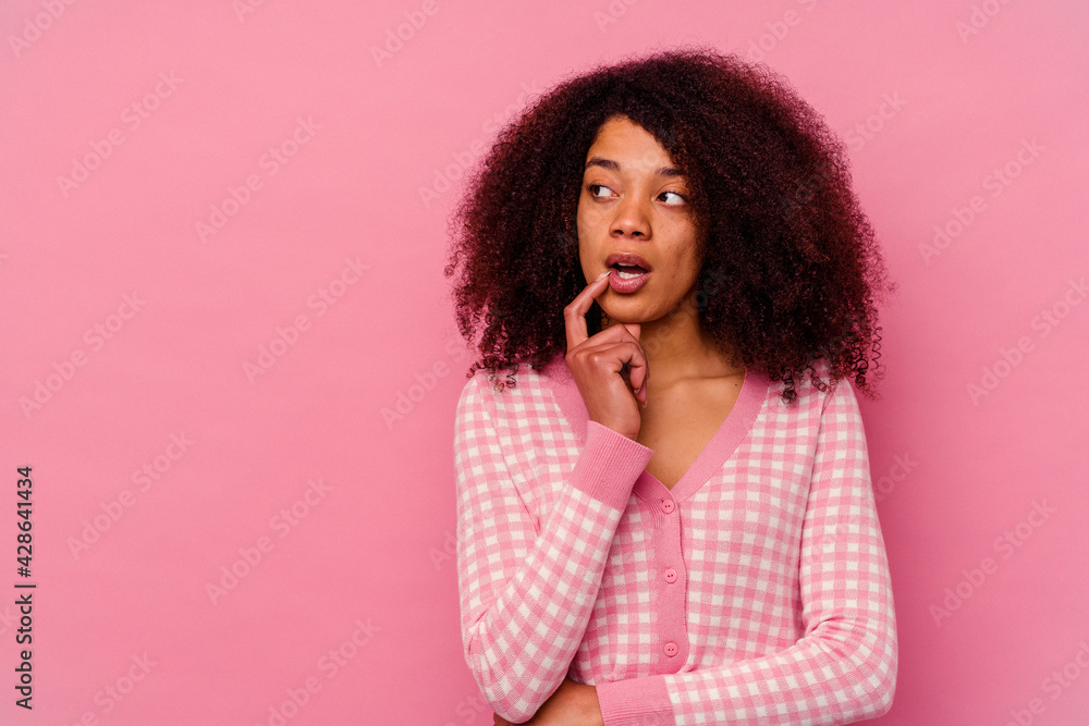 Young african american woman isolated on pink background looking sideways with doubtful and skeptical expression. Young african american woman isolated on pink background looking sideways with doubtful and skeptical expression.