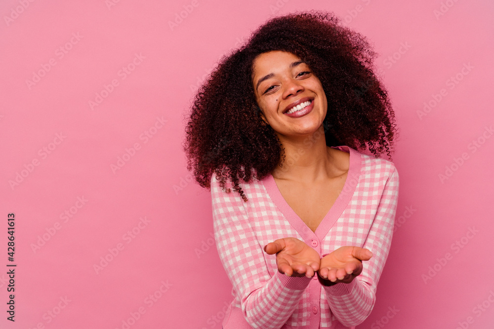 Young african american woman isolated on pink background folding lips and holding palms to send air kiss. Young african american woman isolated on pink background folding lips and holding palms to send air kiss.