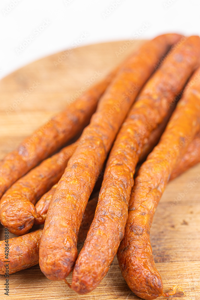 Fresh raw smoked sausages on the wooden cutting board Fresh raw smoked sausages on the wooden cutting board