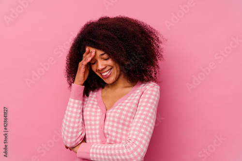 Young african american woman isolated on pink background blink at the camera through fingers, embarrassed covering face.