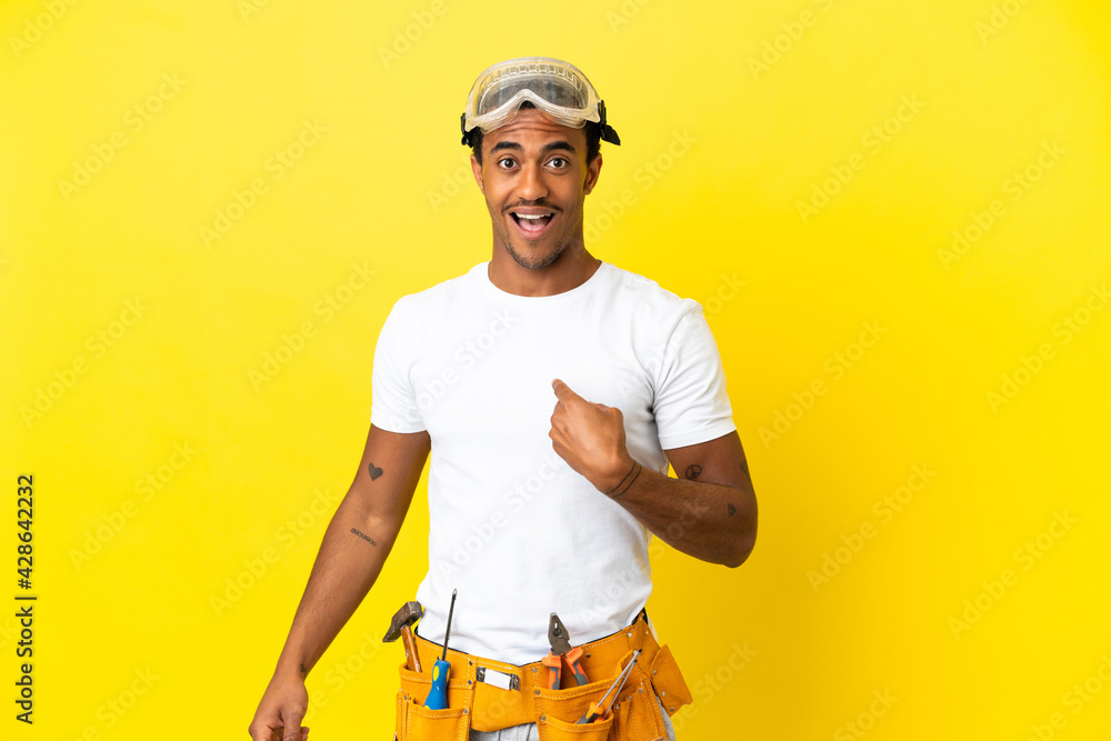 African American electrician man over isolated yellow wall with surprise facial expression African American electrician man over isolated yellow wall with surprise facial expression
