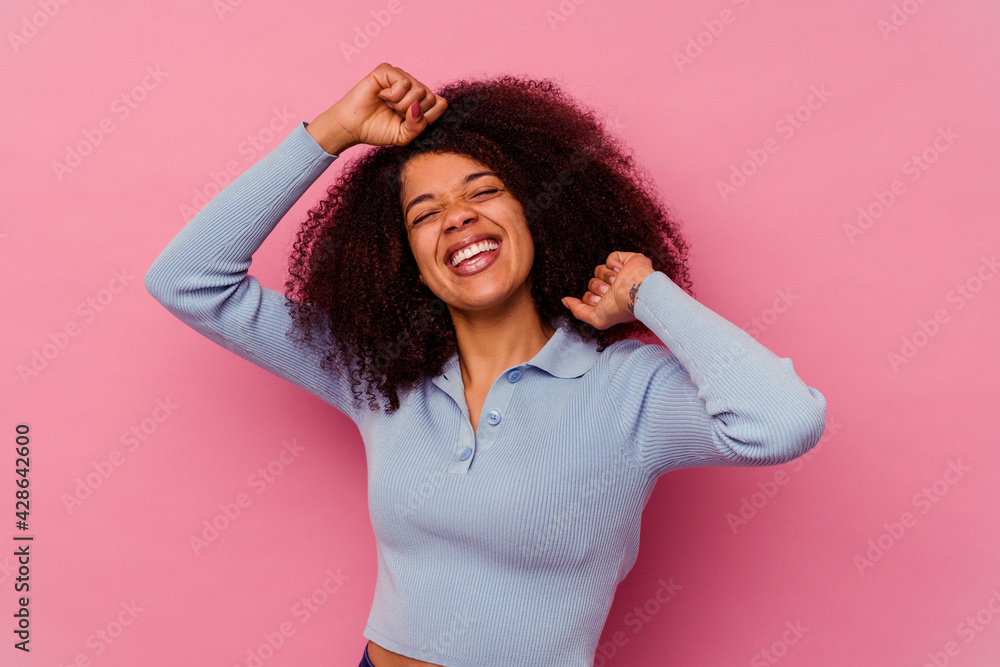 Young african american woman isolated on pink background celebrating a special day, jumps and raise arms with energy. Young african american woman isolated on pink background celebrating a special day, jumps and raise arms with energy.