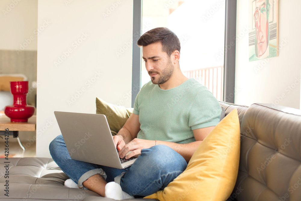 young handsome man using a laptop - obrazy, fototapety, plakaty 