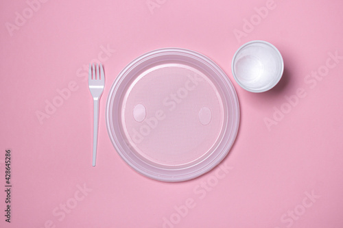 Plastic dishes on a pink background. Disposable tableware. Plastic products.