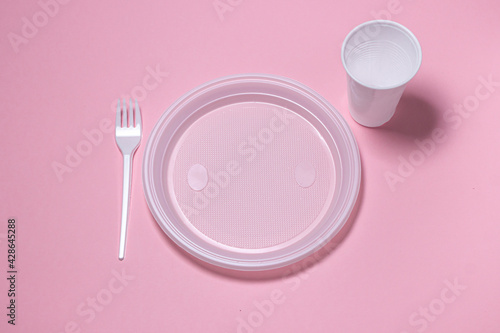 Plastic dishes on a pink background. Disposable tableware. Plastic products.