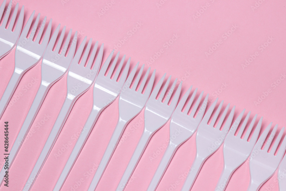 Plastic forks on a pink background. Disposable tableware. Plastic products. Plastic forks on a pink background. Disposable tableware. Plastic products.