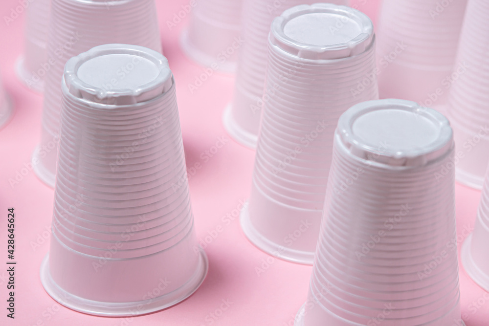 Plastic glasses on a pink background. Disposable tableware. Plastic products. Plastic glasses on a pink background. Disposable tableware. Plastic products.