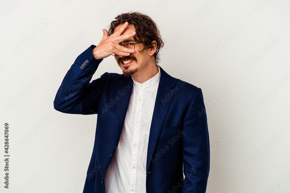 Young business man isolated on white background blink at the camera through fingers, embarrassed covering face. Young business man isolated on white background blink at the camera through fingers, embarrassed covering face.