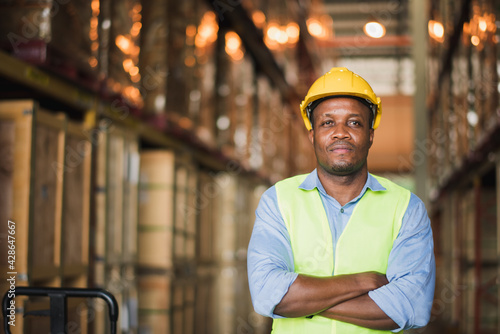 Portrait Young African American man worker stand near shelf box in warehouse factory store to check stock and product which smile and felling happy, logistic and transportation concept