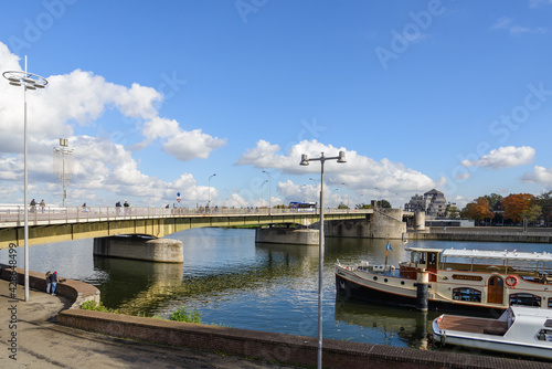 Outdoor sunny view riverside of Meuse river, boat at pier and background of cityscape and Wilhelminabrug bridge in Maastricht, Netherlands. photo