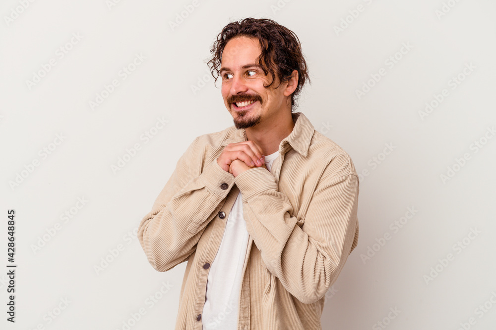 Young caucasian man isolated on white background keeps hands under chin, is looking happily aside. Young caucasian man isolated on white background keeps hands under chin, is looking happily aside.