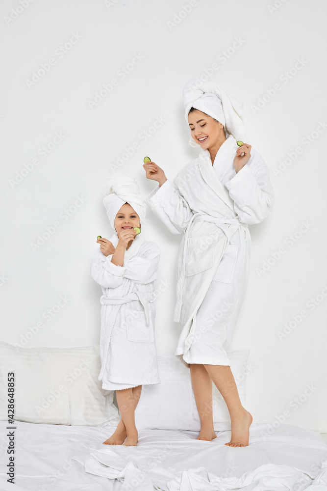 happy woman with daughter holding fresh cucumber slices happy woman with daughter holding fresh cucumber slices