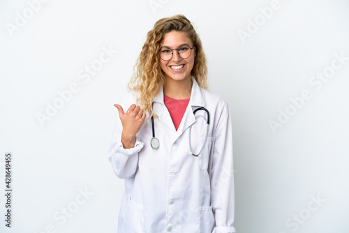 Young doctor blonde woman isolated on white background pointing to the side to present a product