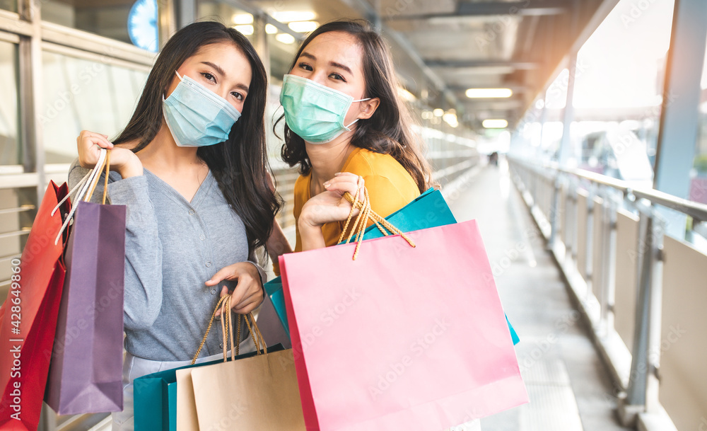 Happy woman with shopping bags enjoying in shopping. Girl holding colour paper bag.Friends walking in shopping mall.time shopping coronavirus crisis or covid19 outbreak. Happy woman with shopping bags enjoying in shopping. Girl holding colour paper bag.Friends walking in shopping mall.time shopping coronavirus crisis or covid19 outbreak.