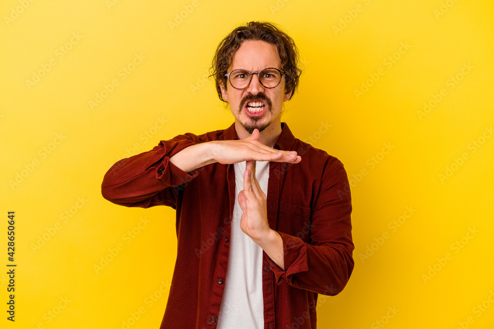 Young caucasian man isolated on yellow background showing a timeout gesture. Young caucasian man isolated on yellow background showing a timeout gesture.