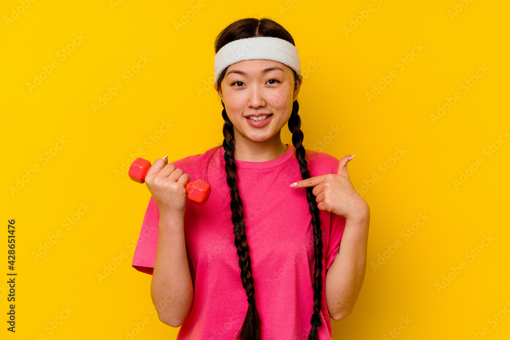 Young sport chinese woman isolated on yellow background person pointing by hand to a shirt copy space, proud and confident Young sport chinese woman isolated on yellow background person pointing by hand to a shirt copy space, proud and confident