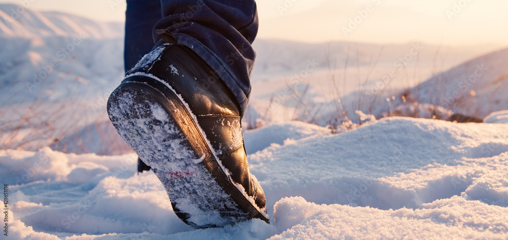 men's feet in boots in the snow walking in winter