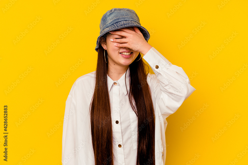 Young chinese woman isolated on yellow background covers eyes with hands, smiles broadly waiting for a surprise. Young chinese woman isolated on yellow background covers eyes with hands, smiles broadly waiting for a surprise.