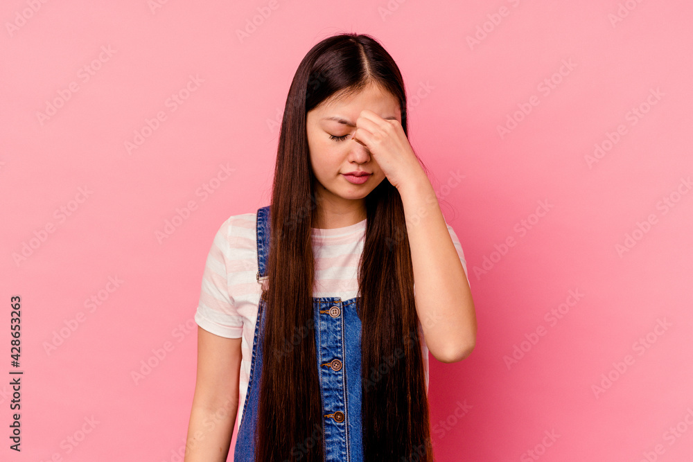 Young chinese woman isolated on pink background having a head ache, touching front of the face. Young chinese woman isolated on pink background having a head ache, touching front of the face.