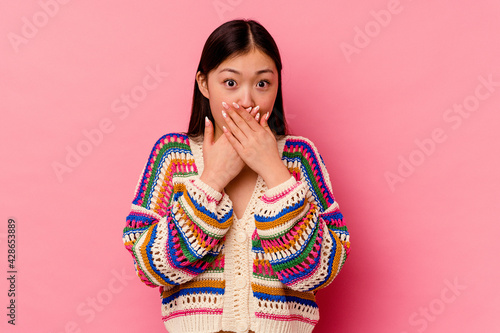 Young chinese woman isolated on pink background shocked covering mouth with hands. photo