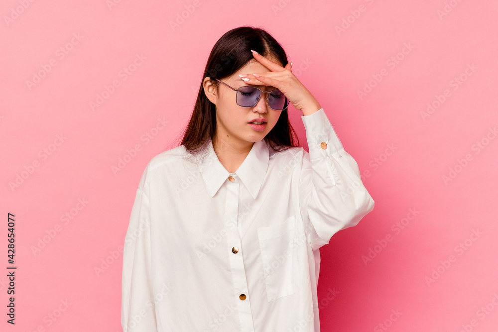 Young chinese woman isolated on pink background touching temples and having headache.