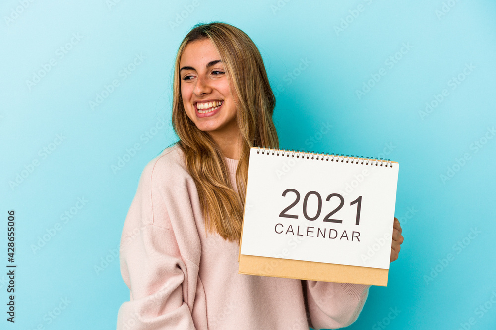 Young blonde caucasian woman holing a calendar isolated looks aside smiling, cheerful and pleasant. Young blonde caucasian woman holing a calendar isolated looks aside smiling, cheerful and pleasant.