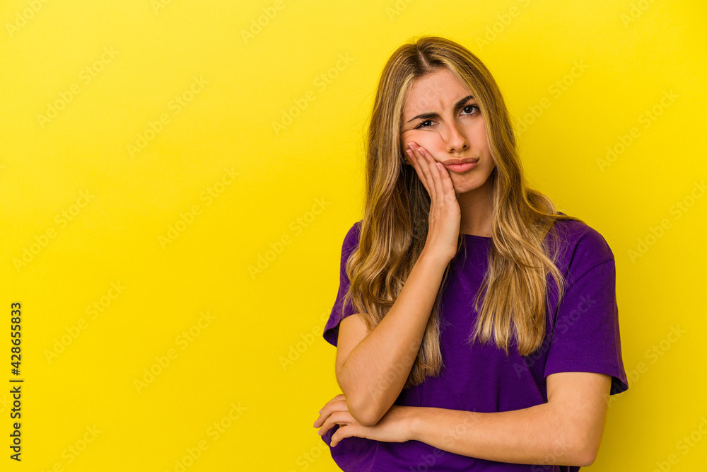 Young blonde caucasian woman isolated on yellow background who feels sad and pensive, looking at copy space. Young blonde caucasian woman isolated on yellow background who feels sad and pensive, looking at copy space.