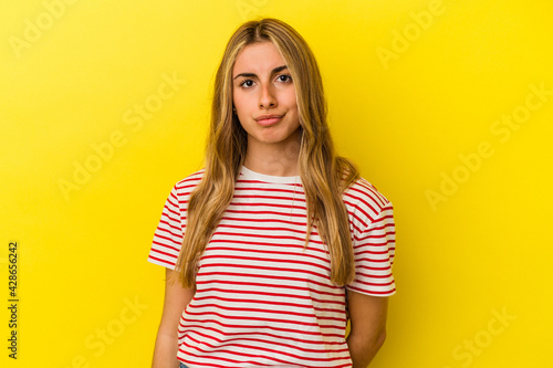 Young blonde caucasian woman isolated on yellow background sad, serious face, feeling miserable and displeased.