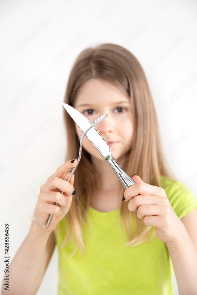 Girl with crossed knife and fork isolated on the white background Girl with crossed knife and fork isolated on the white background