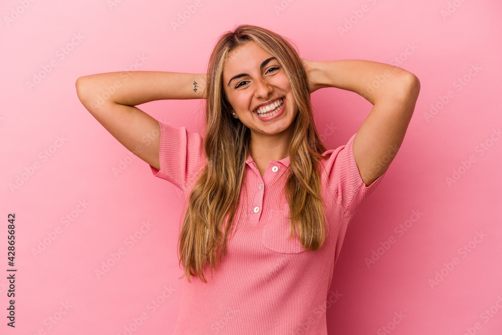 Young blonde caucasian woman isolated on pink background feeling confident, with hands behind the head. Young blonde caucasian woman isolated on pink background feeling confident, with hands behind the head.