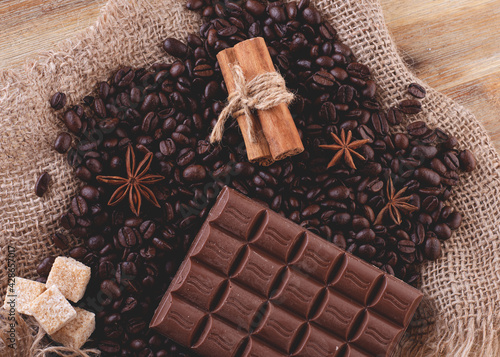 chocolate, coffee beans, anise and cinnamon on wooden background