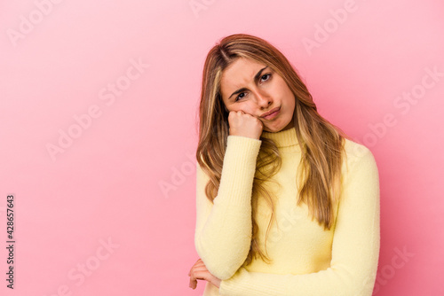 Young blonde caucasian woman isolated on pink background who feels sad and pensive, looking at copy space.