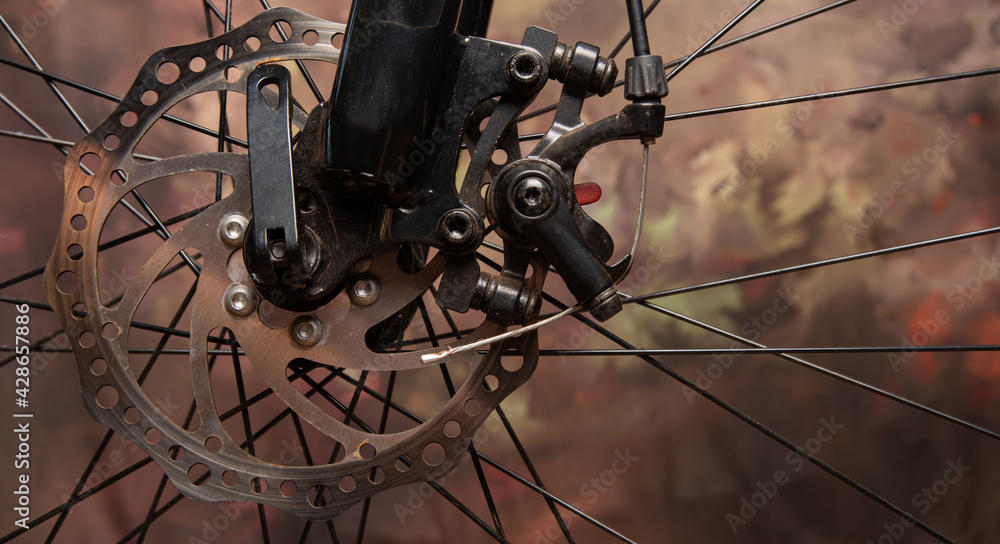 Bicycle details, disc brake and spokes details, dark abstract background, selective focus. Bicycle details, disc brake and spokes details, dark abstract background, selective focus.
