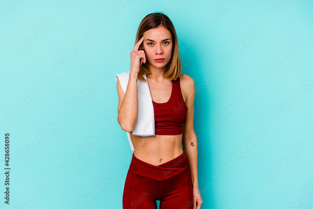 Young sport caucasian woman isolated on blue background pointing temple with finger, thinking, focused on a task. Young sport caucasian woman isolated on blue background pointing temple with finger, thinking, focused on a task.