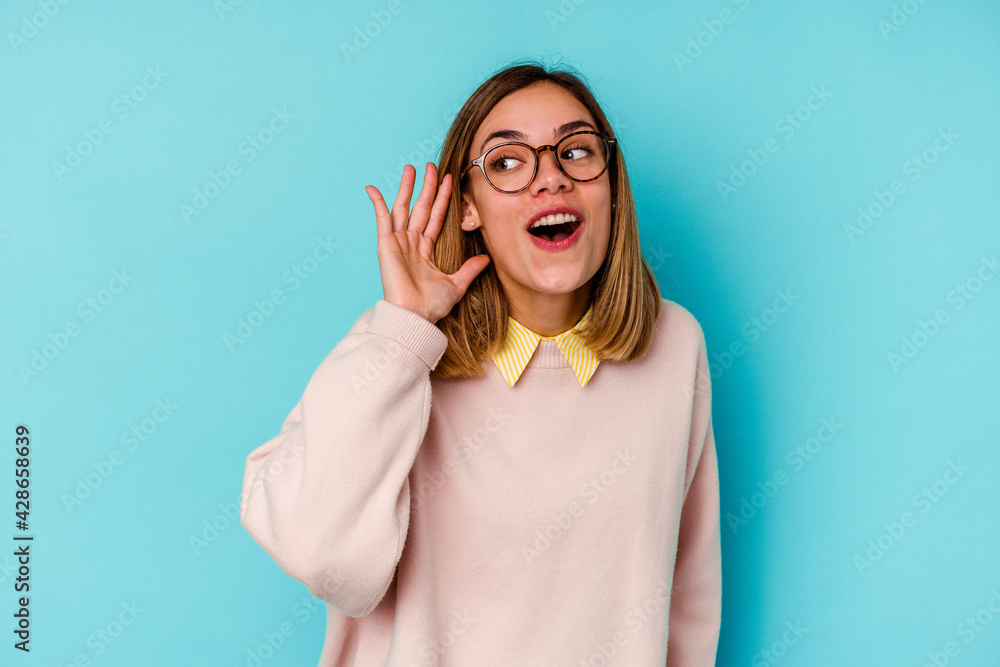 Young student caucasian woman isolated on blue background trying to listening a gossip. Young student caucasian woman isolated on blue background trying to listening a gossip.