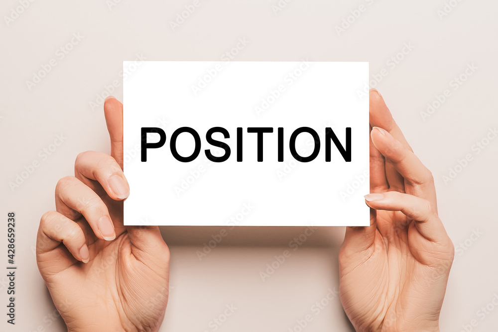 Female hands hold card paper with text POSITION on a yellow background. Business and finance concept Female hands hold card paper with text POSITION on a yellow background. Business and finance concept