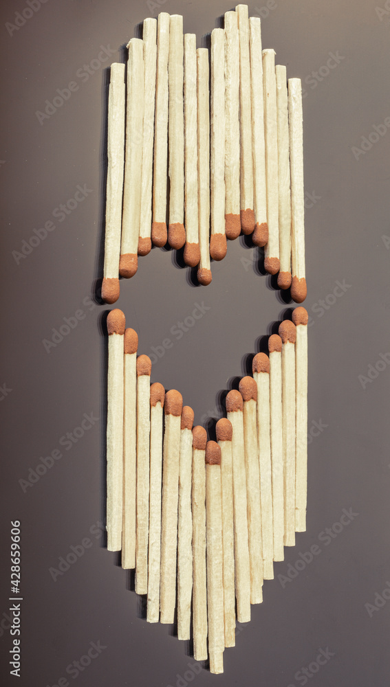 Matches formed as a heart on dark grey background. Matchsticks in the shape of a heart. Conceptual image. Matches formed as a heart on dark grey background. Matchsticks in the shape of a heart. Conceptual image.